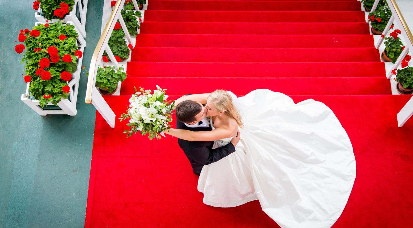A top-view married couple kissing at the top of the steps
