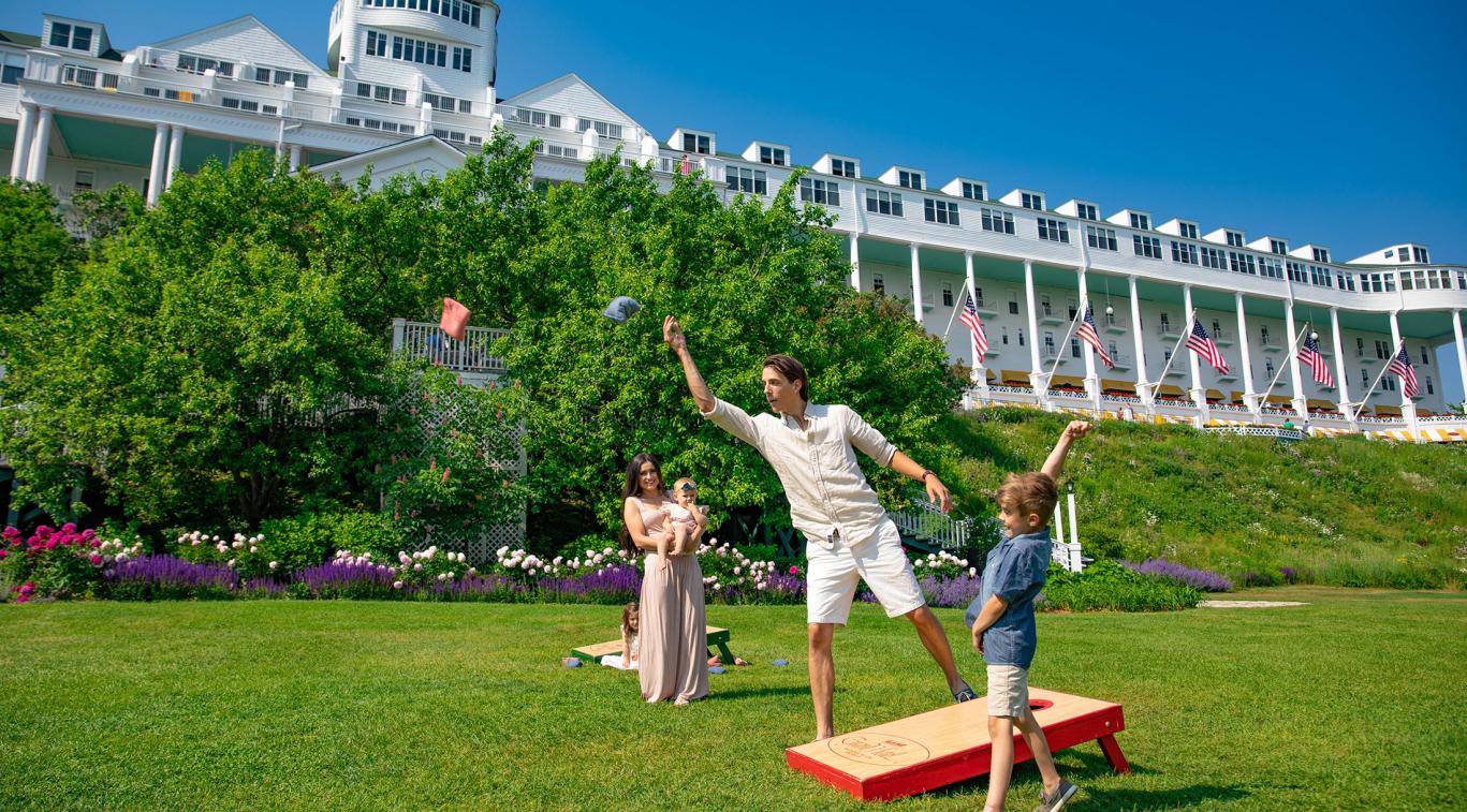 A family playing cornhole on the lawn