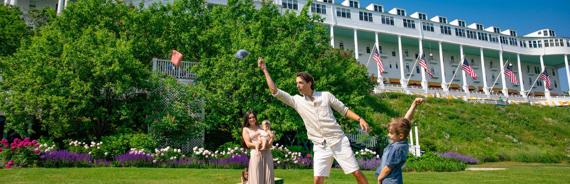 A family playing cornhole on the lawn