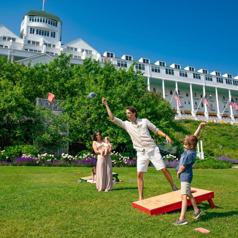 A family playing cornhole on the lawn