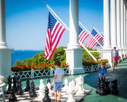 Children playing with large chess board on front porch
