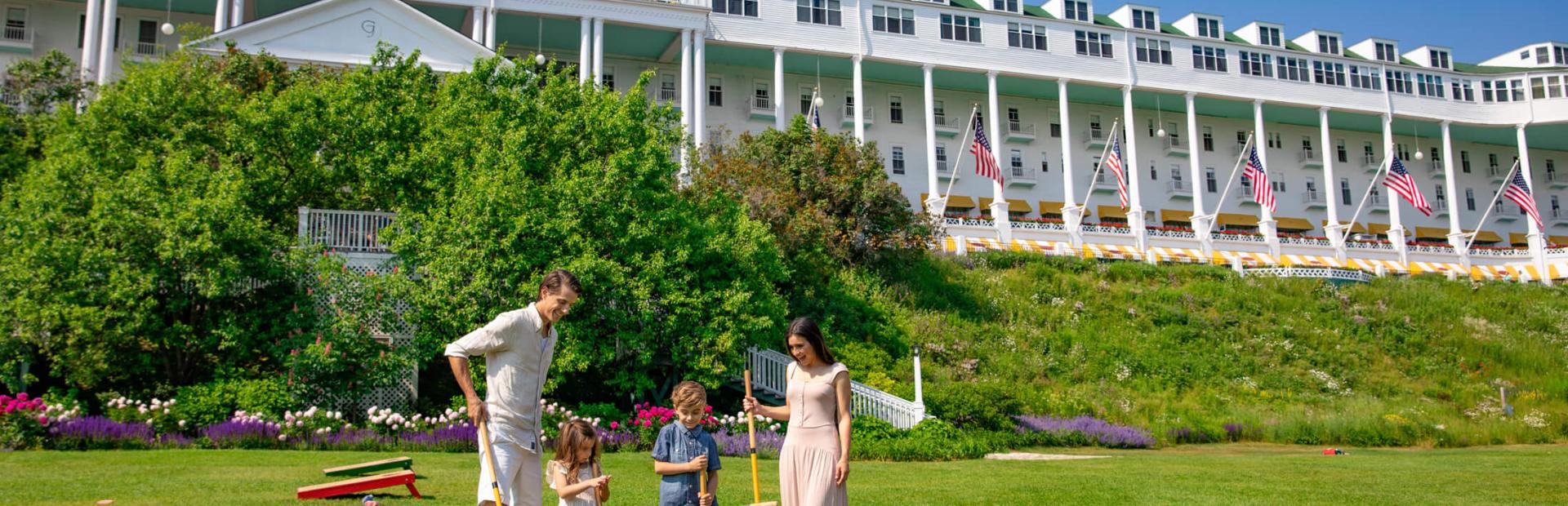 Family playing croquet on front lawn