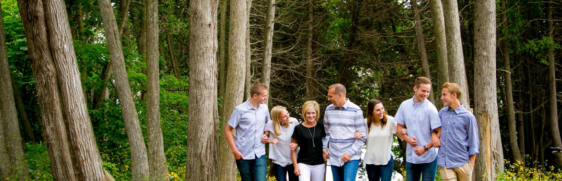 Family linking arms walking through the woods