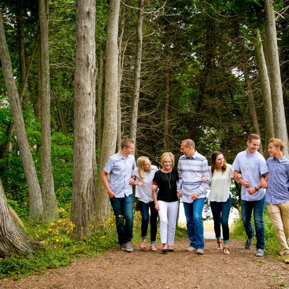 Family linking arms walking through the woods