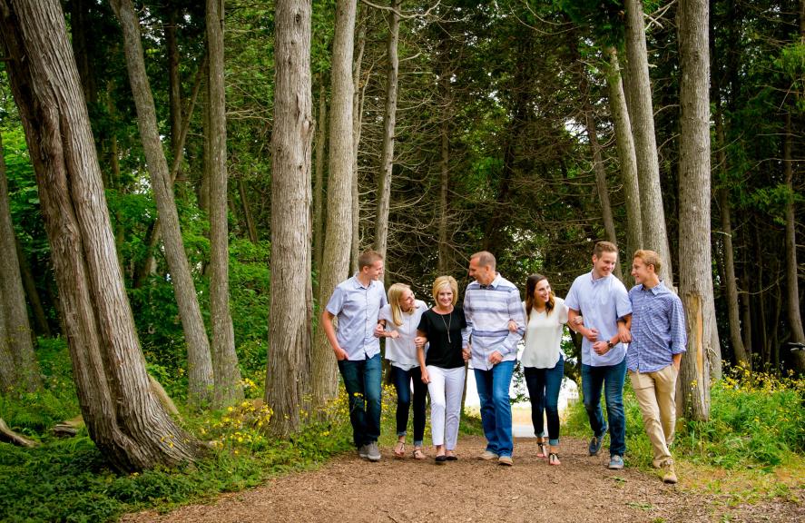 Family linking arms walking through the woods