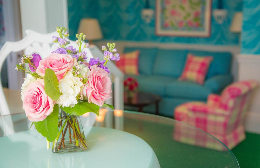 close up of flowers in vase with couch and chair in background