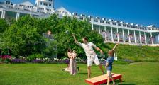 Family playing cornhole on lawn in front of Grand Hotel