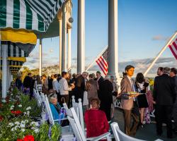 Large group of people mingling on the front porch of Grand Hotel