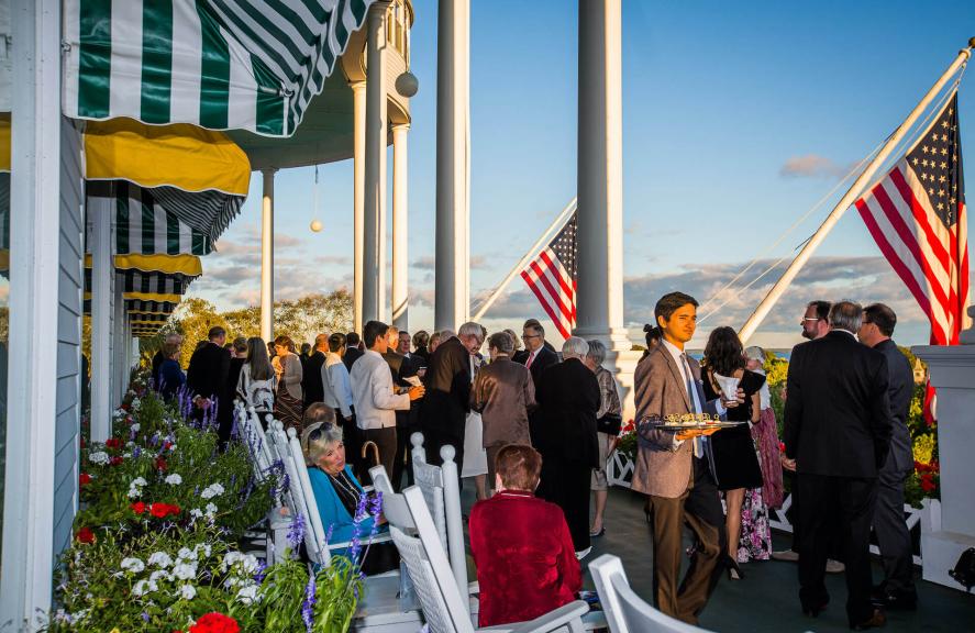 Large group of people mingling on the front porch of Grand Hotel