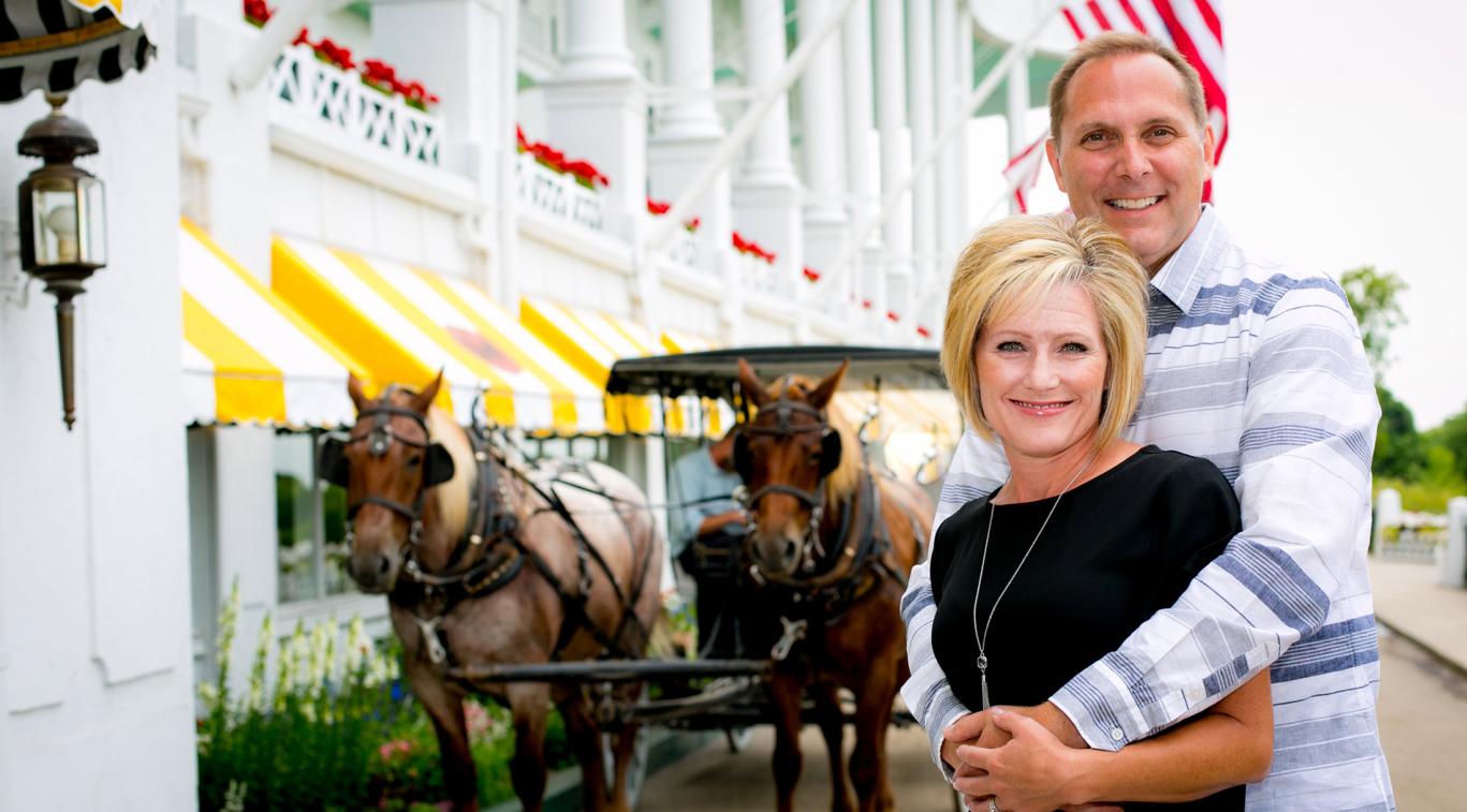 A couple posing in front of a horse carriage