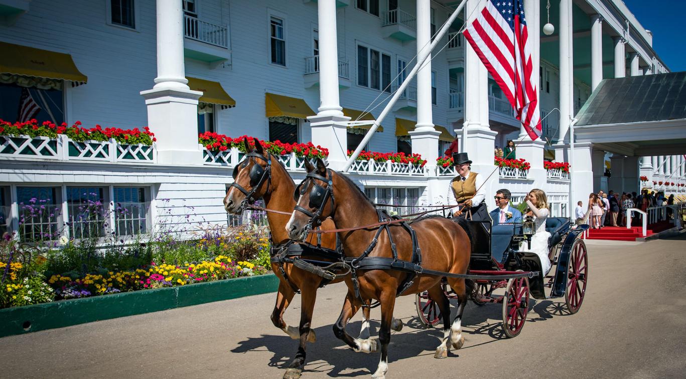 Bride and groom in horse drawn carriage in front of Grand Hotel