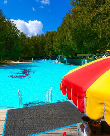 A yellow and red parasol in front of the pool