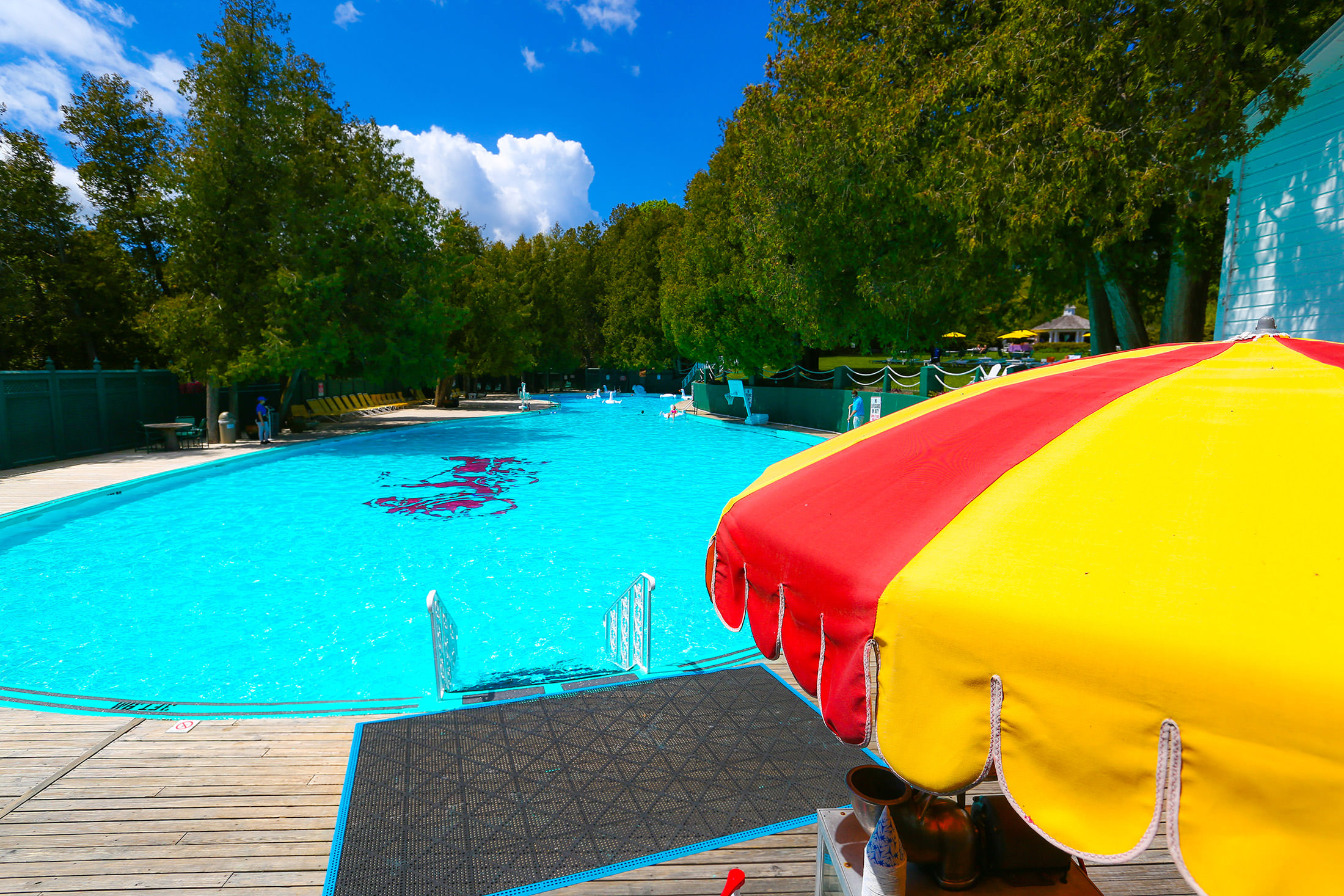 A yellow and red parasol in front of the pool