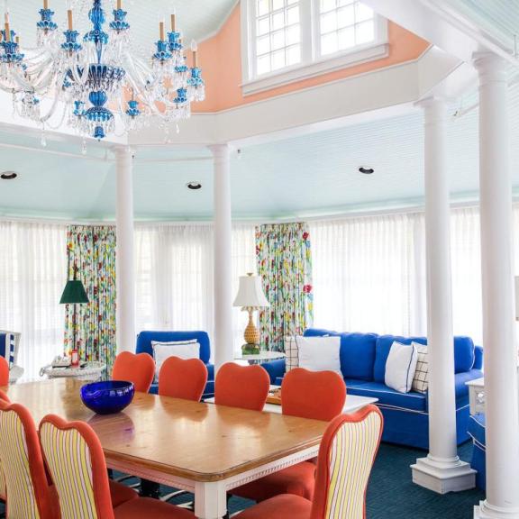 The vibrant interior of the Carleton Varney Suite at Grand Hotel, showing the view from a yellow parlor through to a sitting room with bold red carpet.