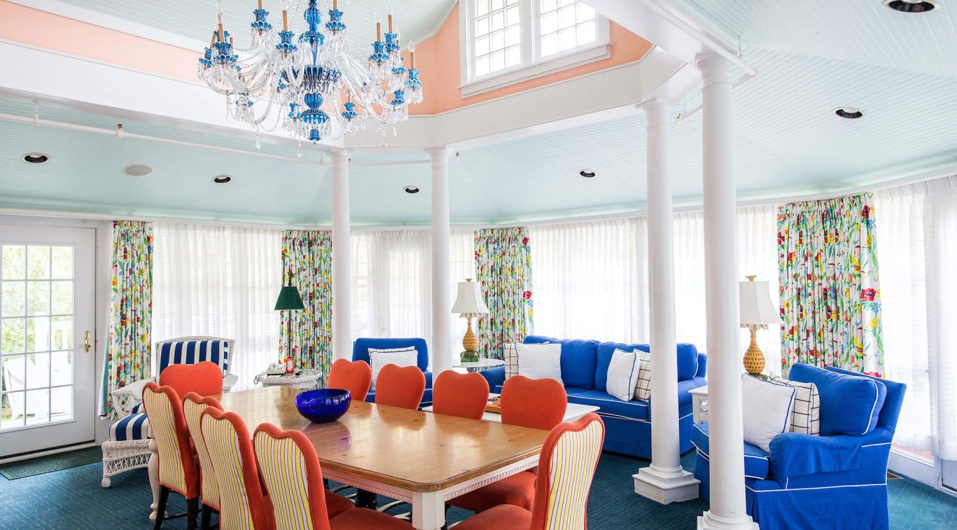 The vibrant interior of the Carleton Varney Suite at Grand Hotel, showing the view from a yellow parlor through to a sitting room with bold red carpet.
