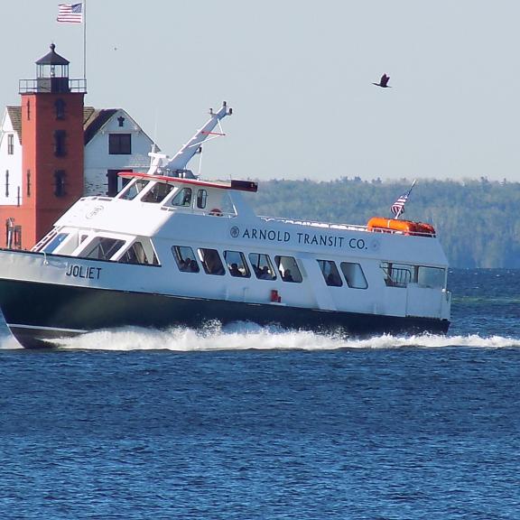 The Arnold Transit Co. ferry 'Joliet' cruises through the Straits of Mackinac, passing the historic Round Island Lighthouse on its way to Mackinac Island.