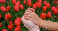A proposal image in front of tulips. Highlighting the engagement ring.